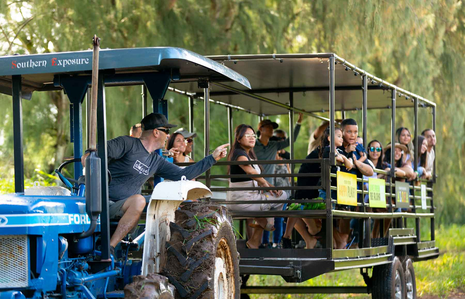 Group of people on a North Shore guided tour in a tractor with a canopy, surrounded by greenery.