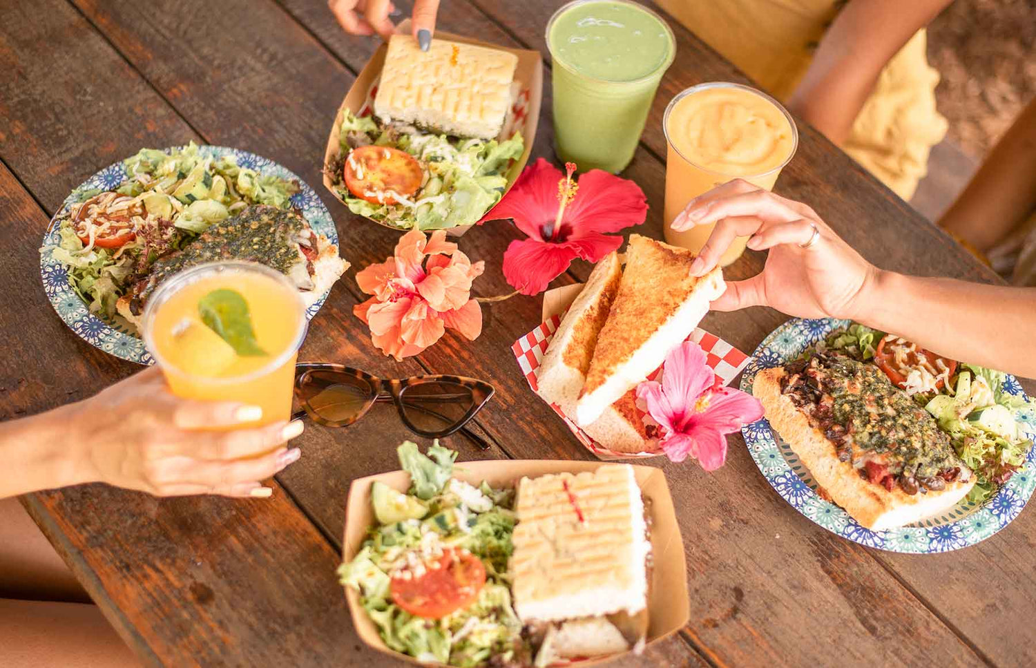 People enjoying a meal with sandwiches, salads, and drinks at the Kahuku Farms cafe