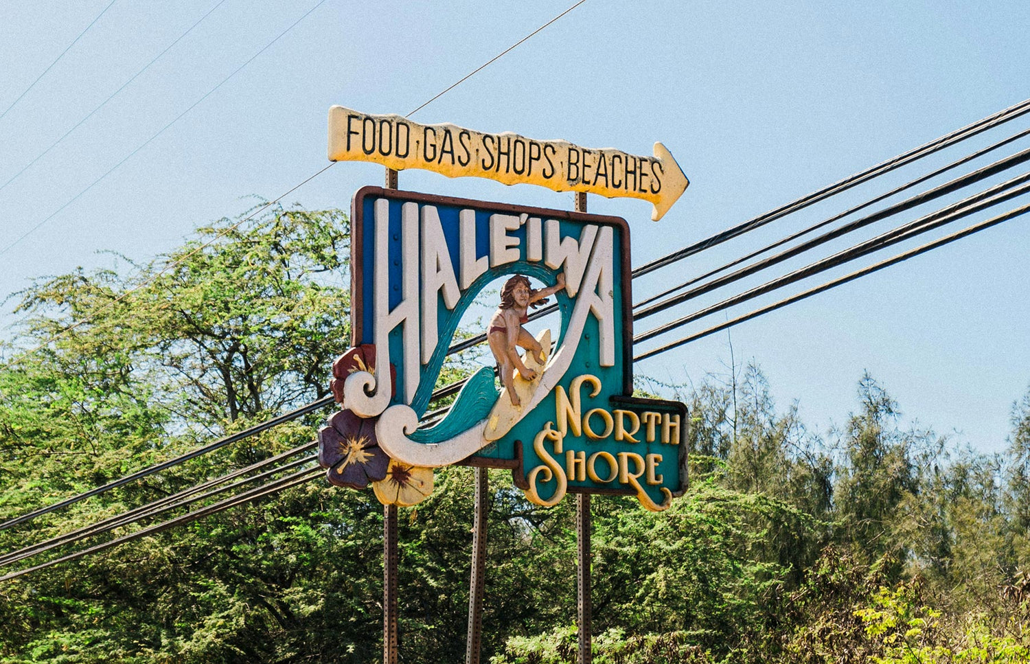 Haleiwa North Shore sign with directional arrows against a clear sky.