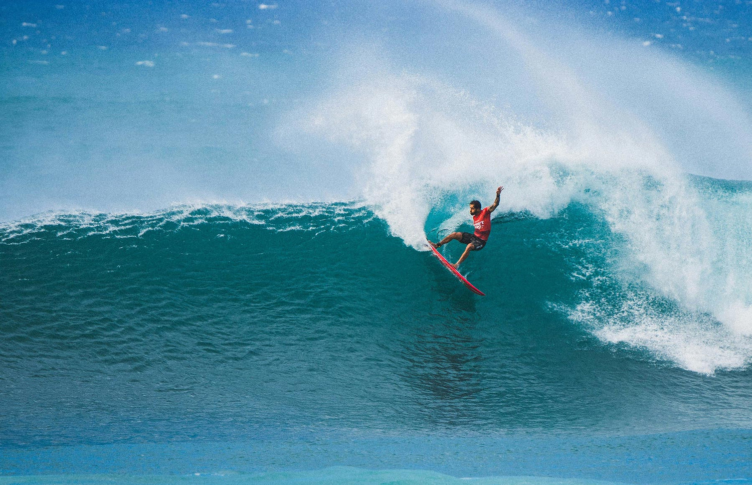 Surfer riding a large wave at Pipeline on Hawaii's North Shore in clear blue water